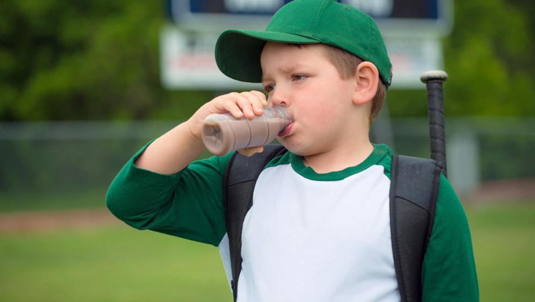 Un jeune baseballeur boit du lait au chocolat