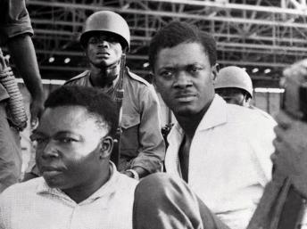 Patrice Lumumba (D), le 30 juin 1960 à Leopoldville, aux côtés du vice-président du Sénat Joseph Okito, entourés de soldats. AFP PHOTO / STRINGER