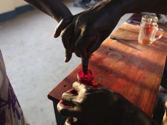 Une femme trempe son doigt dans un bocal d'encre indélébile, après avoir voté lors du référendum sur l'autodétermination d'Abyei, le 28 octobre 2013. REUTERS/Andreea Campeanu
