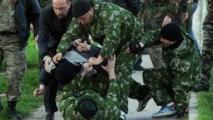 Des soldats russes arrêtant de force un soldat ukrainien sans prévenir.