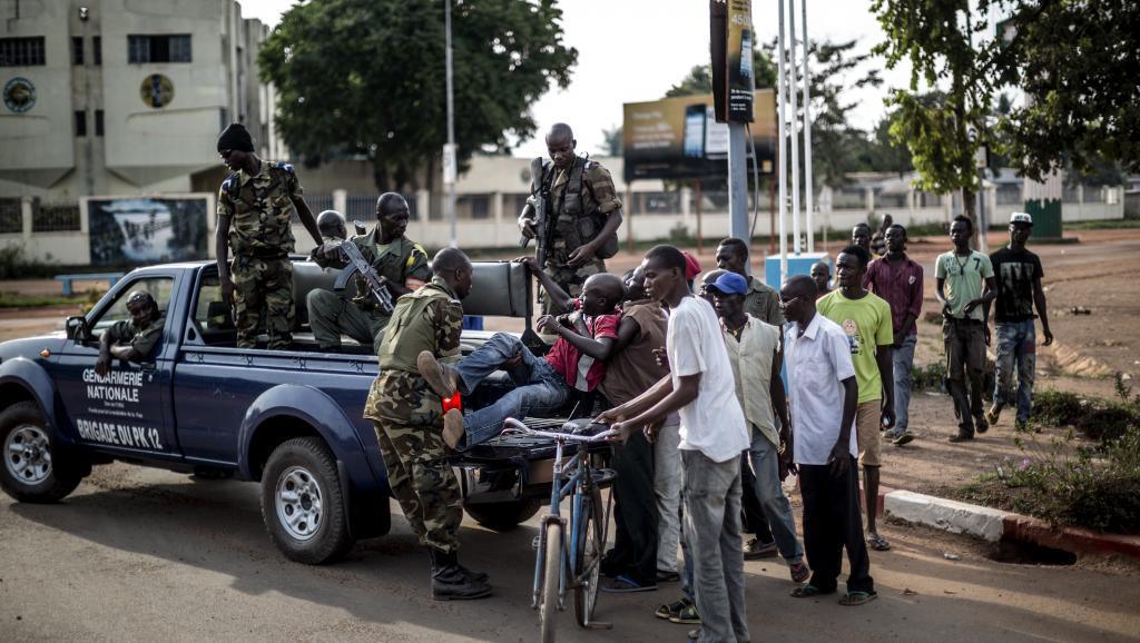 Des membres de la gendarmerie nationale évacuent un blessé vers l'hôpital de Bangui, le 29 mai 2014. AFP PHOTO/MARCO LONGARI