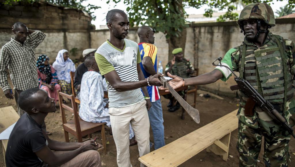 Un habitant du quartier PK5 remet sa machette à un soldat de la Misca. Bangui, le 8 juin 2014. AFP PHOTO/MARCO LONGARI