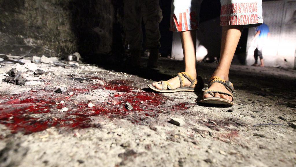 Un jeune homme se tient sur les lieux d'un double attentat suicide qui a tué 4 soldats sur une base militaire à Benghazi, le 22 juillet. AFP PHOTO/Abdullah DOMA