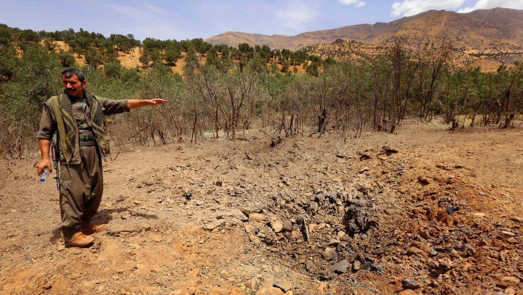Un membre du PKK devant le cratère laissé par un bombardement turc, à Qandil, dans le nord de l'Irak. AFP PHOTO / SAFIN HAMED