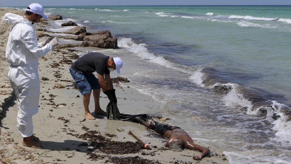 Des employés du Croissant-rouge libyen récupèrent le corps d'un migrant sur la plage de Zouara, le 28 août 2015, quelques heures après le naufrage du bateau. REUTERS/Hani Amara