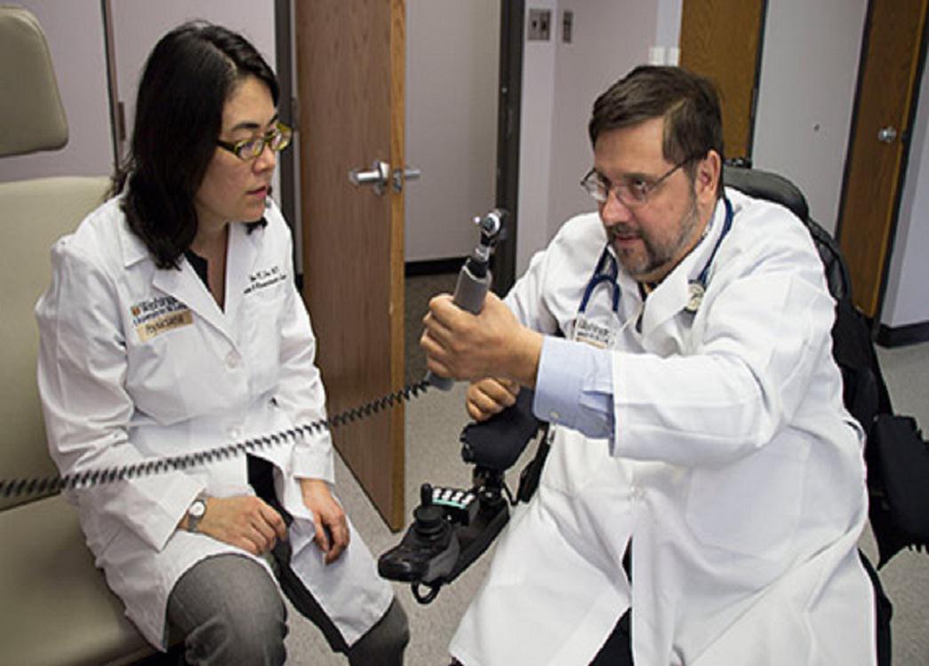 Michael Bavlsik muestra a Ida Fox cómo es capaz de sujetar un otoscopio, tras practicársele la cirugía de transferencia de nervios. Imagen: E. Holland Durand. Fuente: WUSTL.