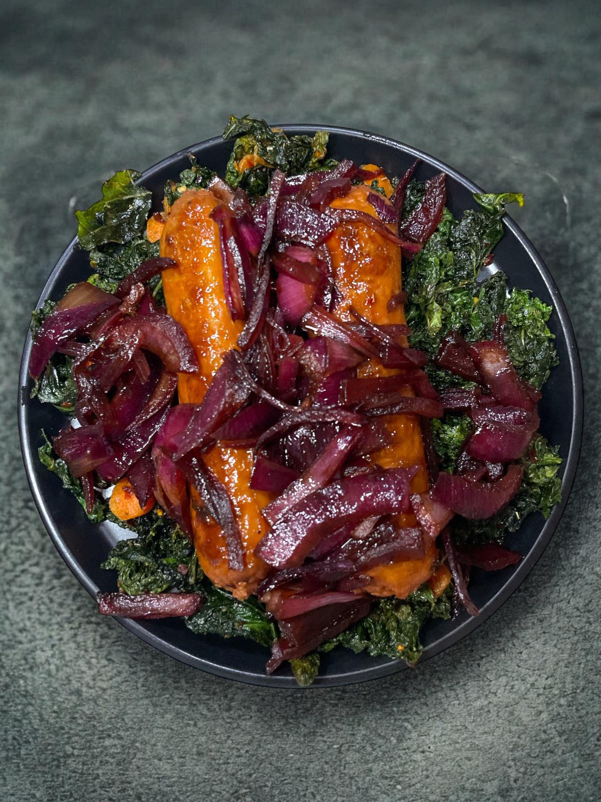 Vegan Italian Sausage on Roasted Kale and Baby Carrots with Caramelized Balsamic Onions