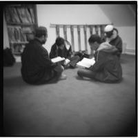 Mosquée Omar (11ème arrondissement), assis en tailleur, de jeunes adultes récitent le coran.