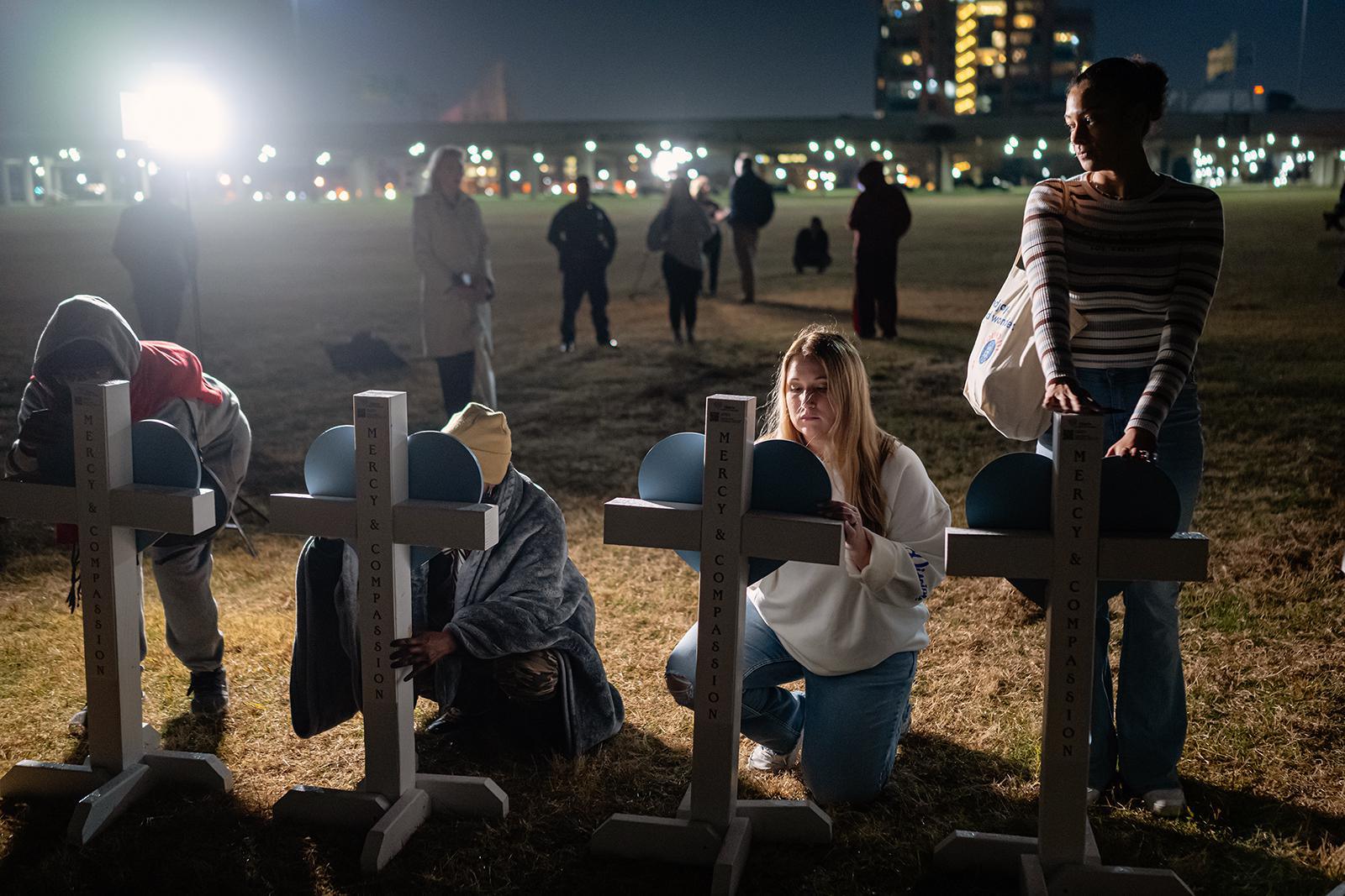 أعضاء من المجتمع يوقعون على لافتات معلقة على صلبان خلال وقفة تأبين لضحايا حادث تحطم طائرة UPS، على العشب