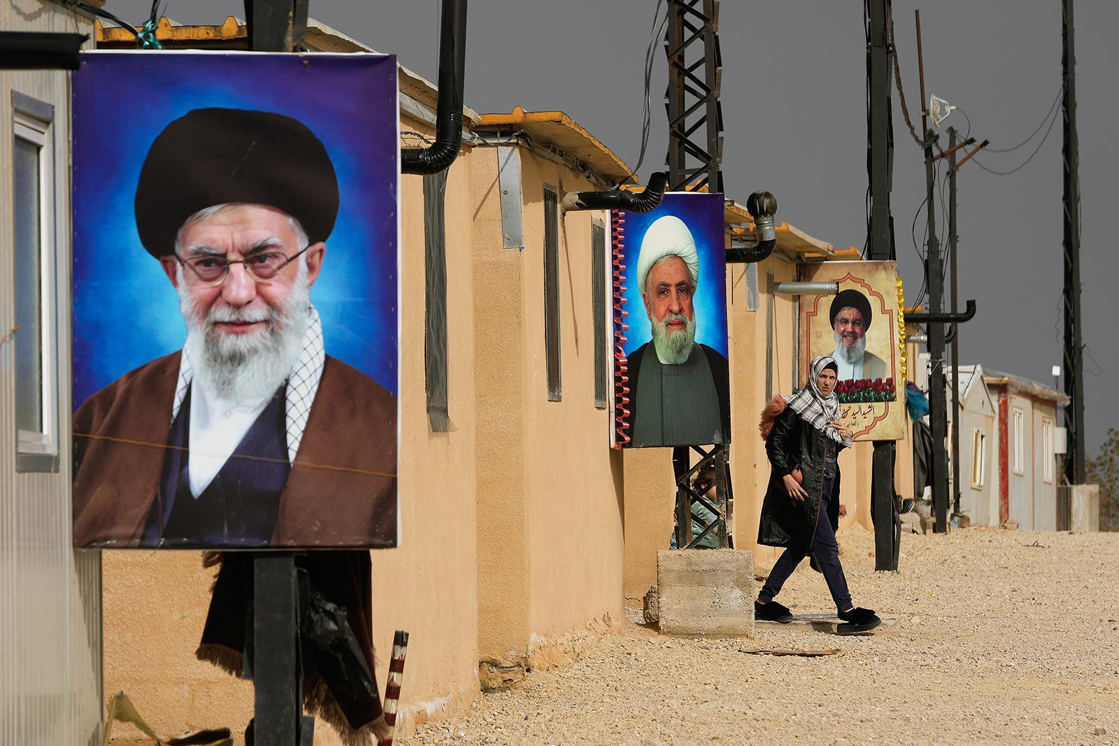 امرأة سورية شيعية تمر أمام صور المرشد الأعلى الإيراني، آية الله علي خامنئي (في المقدمة)، وزعيم حزب الله الشيخ نعيم قاسم (في الوسط)، وزعيم حزب الله الراحل السيد حسن نصر الله (في الخلفية)، في مجمع الإمام علي السكني، الذي يأوي مئات المسلمين الشيعة، معظمهم من اللبنانيين والسوريين، النازحين من سوريا، في الهرمل، شمال شرق لبنان، يوم الجمعة 30 يناير/كانون الثاني 2026. (صورة AP/حسين مالا)