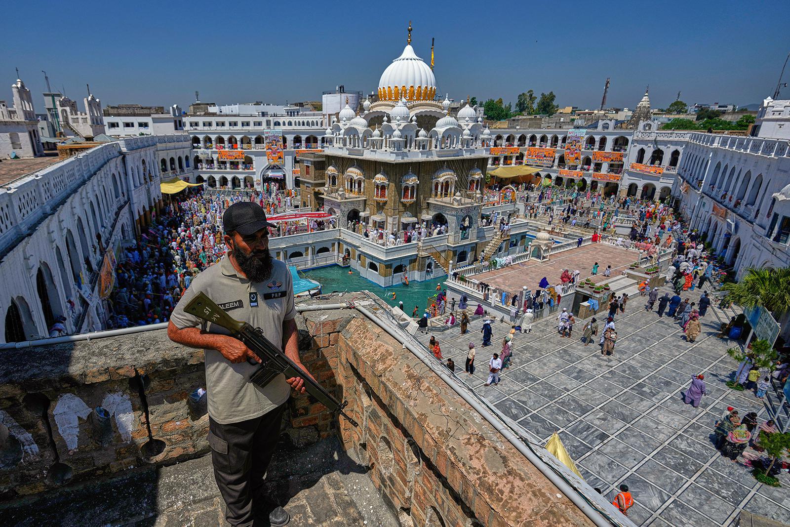 ضابط شرطة يقف حارسًا على سطح مبنى لضمان الأمن بينما يحتفل الحجاج السيخ بمهرجان فيساخي، الذي يمثل أيضًا رأس السنة الجديدة في التقاليد السيخية، في ضريح غوردوارا بونجا صاحب، ثاني أقدس مكان لدى السيخ، في حسن أبدال، باكستان، الثلاثاء 14 أبريل 2026. (صورة من وكالة أسوشيتد برس/أنجوم نافيد) 