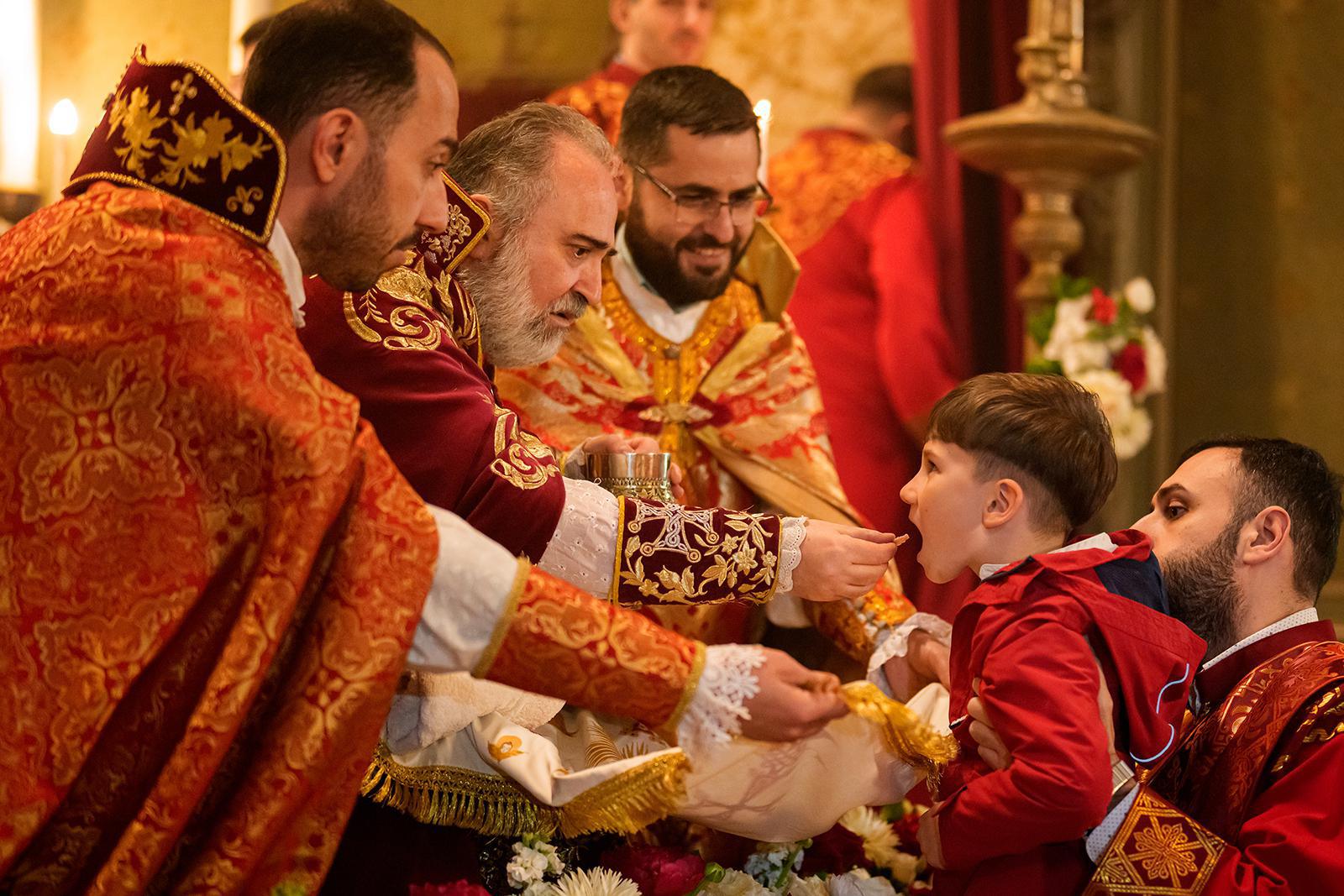 صبي يتناول القربان المقدس من رئيس أساقفة الكنيسة الأرمنية داتيف هاغوبيان خلال قداس عيد الفصح الأرثوذكسي في الكاتدرائية الأرمنية الأرثوذكسية في بوخارست، رومانيا، السبت 11 أبريل/نيسان 2026. (صورة من وكالة أسوشييتد برس/أندريا ألكساندرو) 