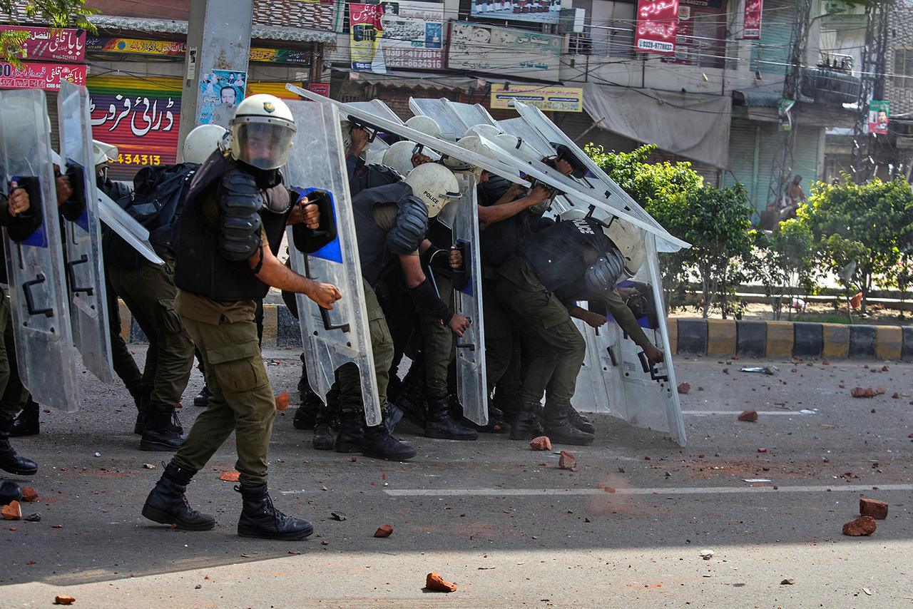 يحتمي أفراد الشرطة خلف دروع للحماية من الحجارة التي يلقيها مؤيدو حزب "تحريك لبيك باكستان" الإسلامي خلال اشتباكات قبل مسيرتهم المؤيدة لفلسطين نحو العاصمة إسلام آباد، في لاهور، باكستان، الجمعة، 10 أكتوبر 2025. (أ ب/ك. م. شوداري)