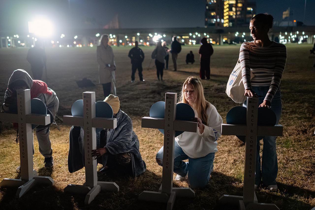 أعضاء من المجتمع يوقعون على لافتات معلقة على صلبان خلال وقفة تأبين لضحايا حادث تحطم طائرة UPS، على العشب